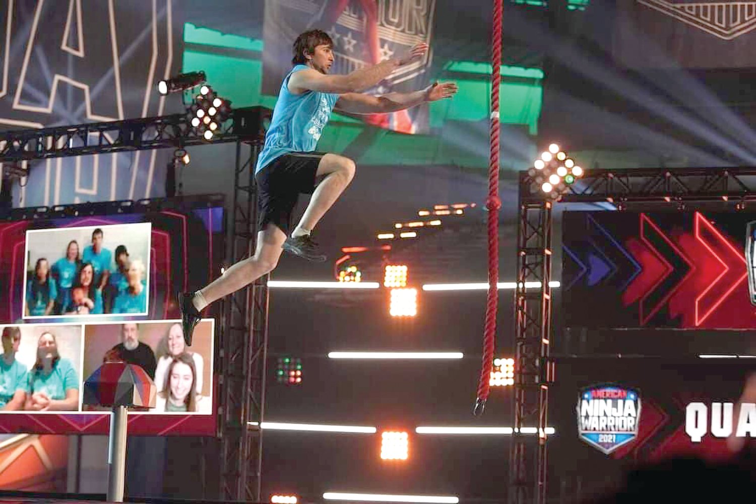 Mountain Grove’s Caleb Dowden leaps for the rope during an obstacle in the first round of the hit television show, American Ninja Warrior, while his family watches on in the background.